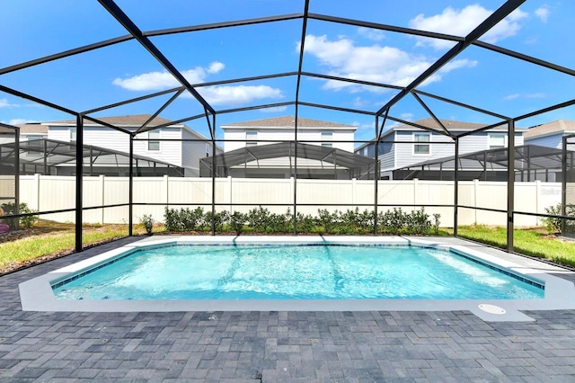 view of pool featuring glass enclosure, a patio area, fence, and a fenced in pool