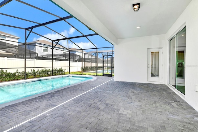 view of swimming pool with glass enclosure, a fenced in pool, and a patio