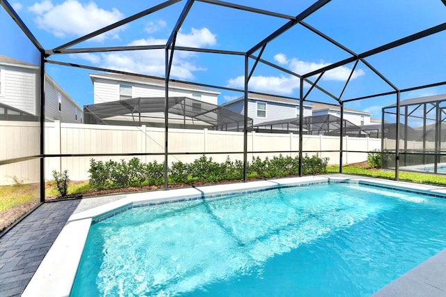 view of pool with glass enclosure, a patio, fence, and a fenced in pool