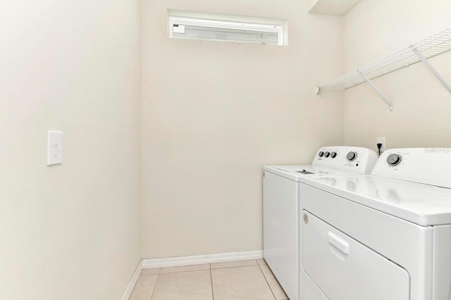 washroom with laundry area, light tile patterned flooring, independent washer and dryer, and baseboards