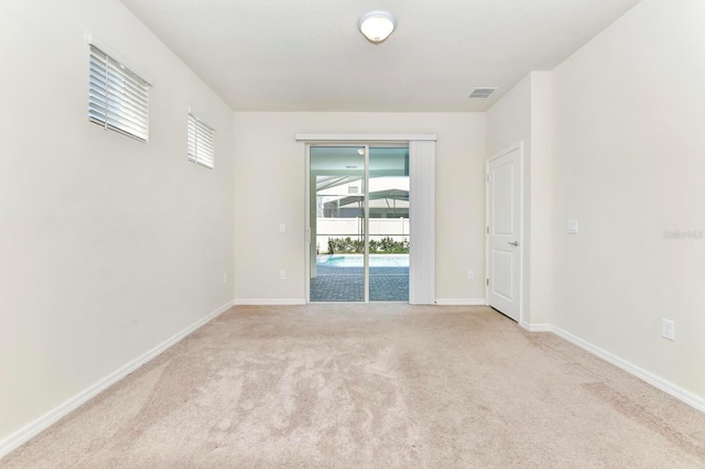 spare room featuring light colored carpet, a healthy amount of sunlight, and baseboards