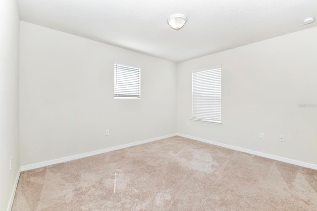 spare room with light carpet and baseboards