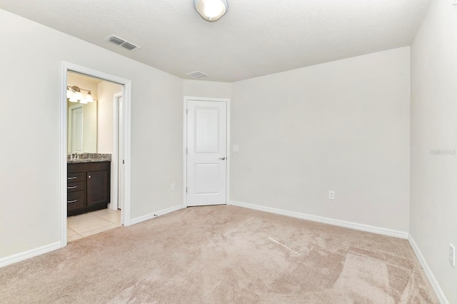 unfurnished bedroom featuring light carpet, baseboards, visible vents, and a sink