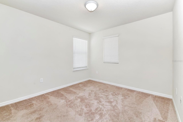 carpeted empty room featuring baseboards