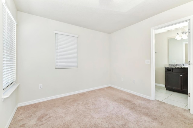 spare room featuring light carpet, light tile patterned floors, and baseboards