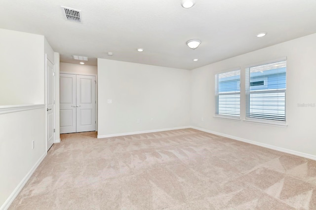 unfurnished room featuring light carpet, baseboards, visible vents, and recessed lighting