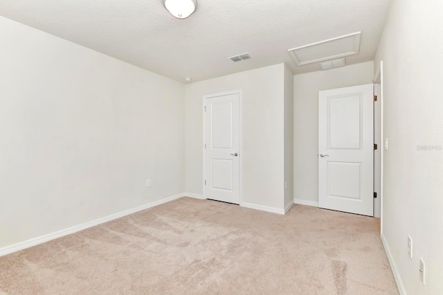 unfurnished bedroom with baseboards, attic access, visible vents, and carpet flooring