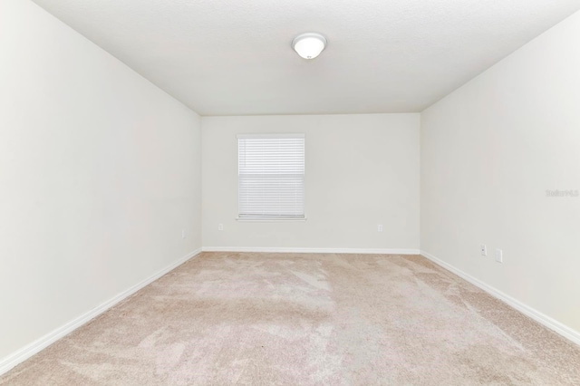 spare room with light colored carpet and baseboards