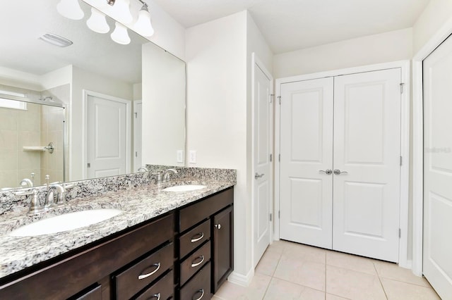 bathroom with double vanity, a stall shower, tile patterned flooring, and a sink