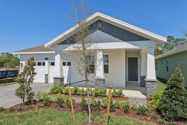 view of front of home featuring stucco siding, decorative driveway, board and batten siding, covered porch, and a garage