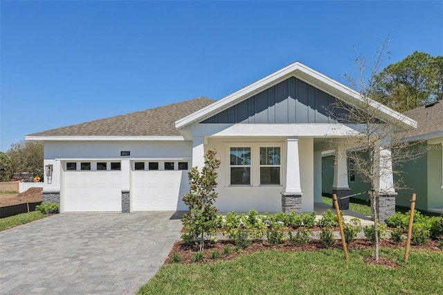 craftsman-style house with board and batten siding, a shingled roof, stucco siding, decorative driveway, and an attached garage