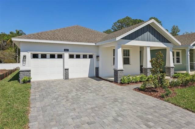 view of front of house featuring stucco siding, decorative driveway, stone siding, roof with shingles, and a garage