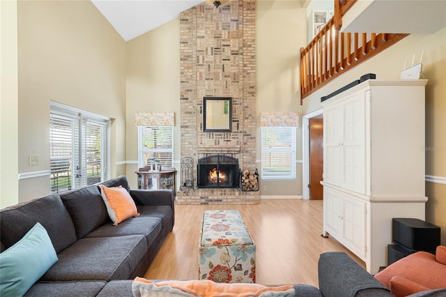 living room with high vaulted ceiling, a brick fireplace, wood finished floors, and baseboards