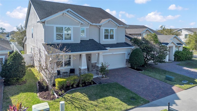 craftsman inspired home featuring a garage, a shingled roof, stone siding, decorative driveway, and a porch