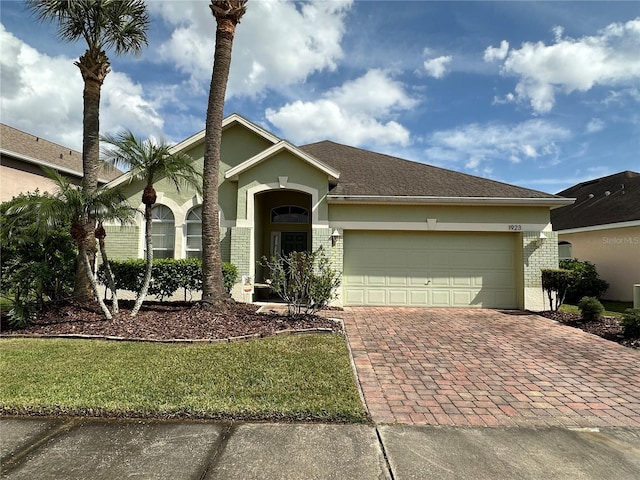 ranch-style house featuring a garage, a front yard, decorative driveway, and brick siding