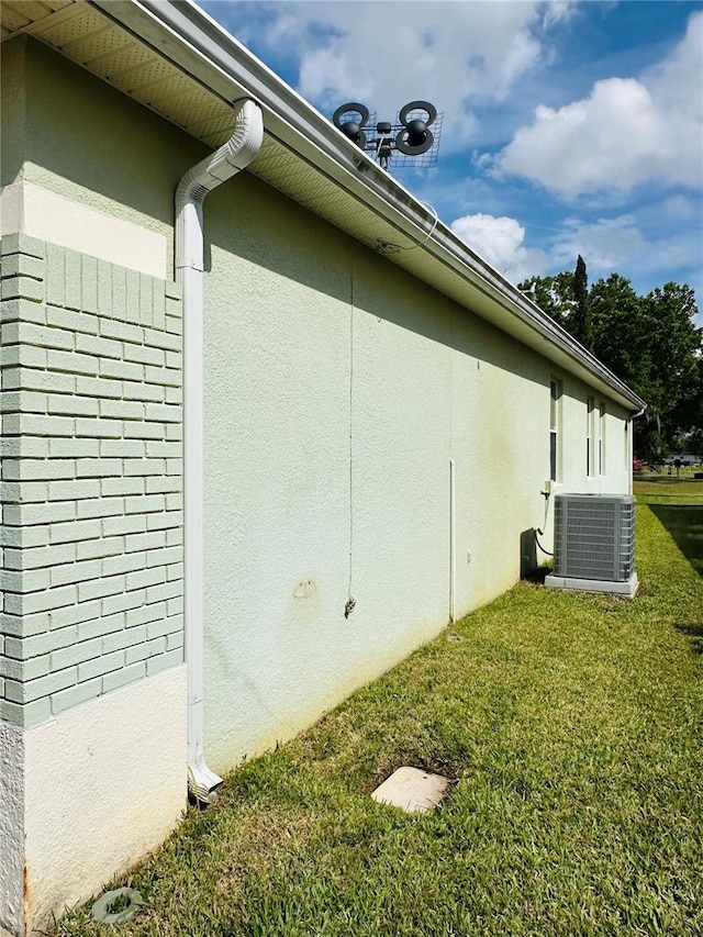 view of side of property featuring cooling unit, a yard, and stucco siding