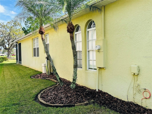 view of side of property featuring a lawn and stucco siding