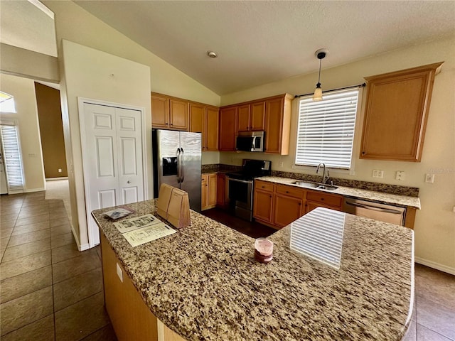 kitchen with lofted ceiling, stainless steel appliances, dark tile patterned flooring, a sink, and hanging light fixtures