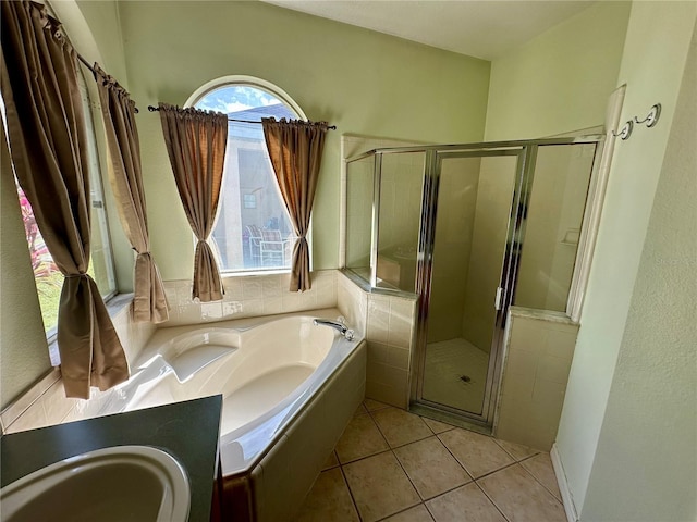 full bath featuring a garden tub, tile patterned flooring, a sink, and a shower stall