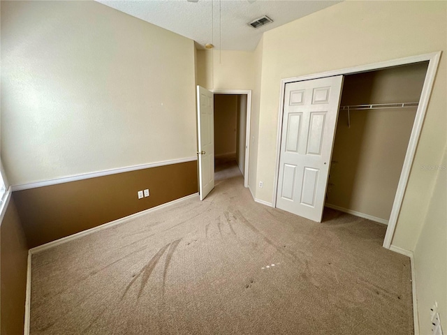 unfurnished bedroom featuring baseboards, visible vents, a textured ceiling, carpet floors, and a closet