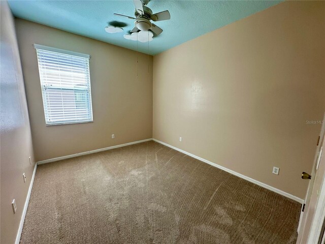 carpeted empty room featuring ceiling fan, baseboards, and a textured ceiling