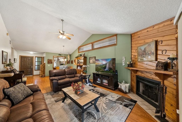 living room featuring a textured ceiling, wood finished floors, a fireplace with flush hearth, and a ceiling fan