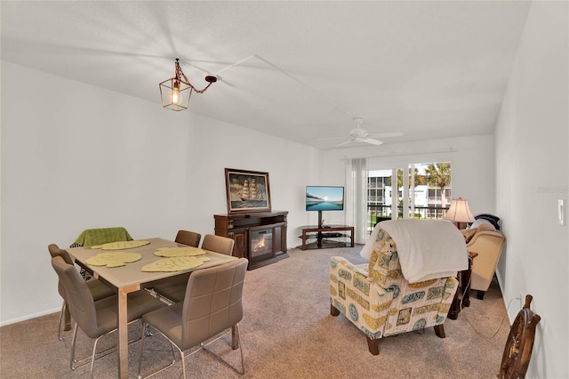 carpeted dining space with a glass covered fireplace and ceiling fan