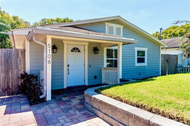 bungalow-style home featuring a front yard, fence, and roof with shingles