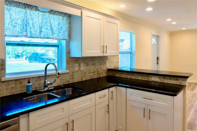 kitchen featuring decorative backsplash, a peninsula, white cabinetry, and a sink