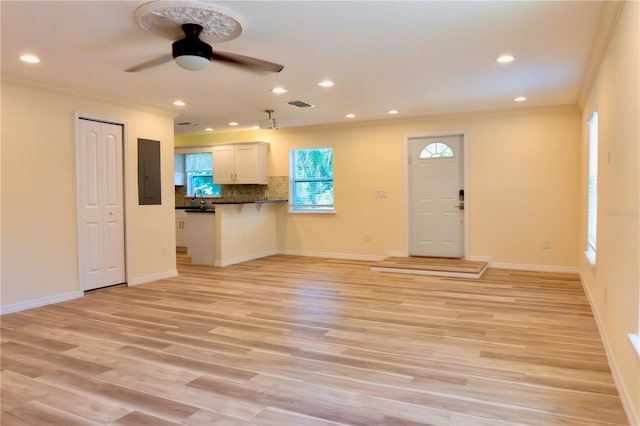 unfurnished living room featuring electric panel, visible vents, light wood-style flooring, and ornamental molding