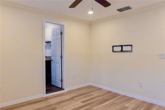 spare room featuring baseboards, visible vents, light wood-style flooring, ceiling fan, and crown molding