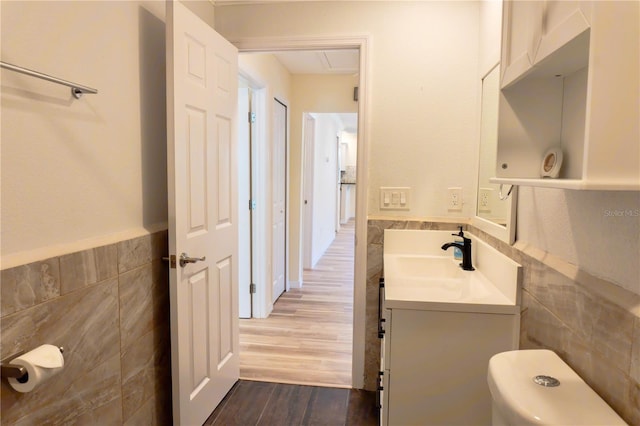 half bath with vanity, tile walls, and wood finished floors