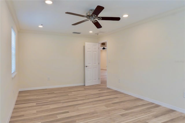 spare room with visible vents, baseboards, light wood-style floors, and ornamental molding