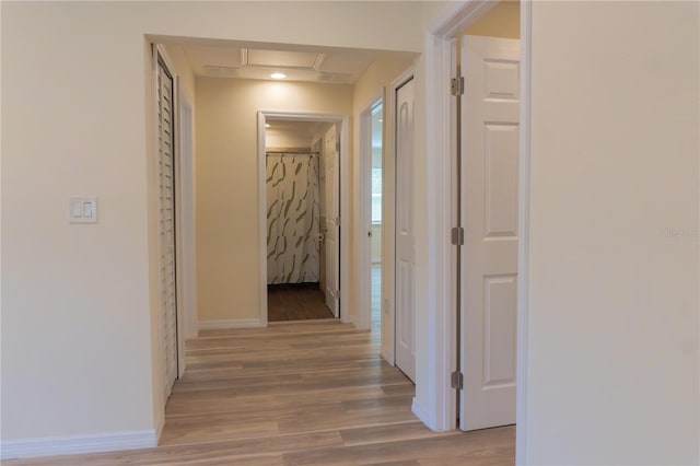 corridor featuring light wood finished floors and baseboards