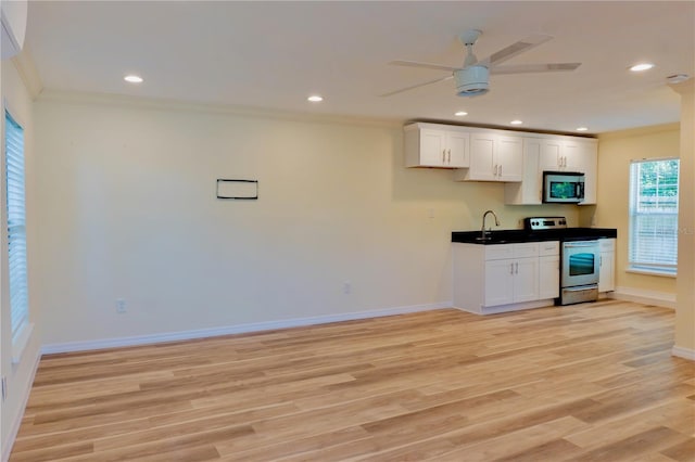 kitchen with appliances with stainless steel finishes, light wood-type flooring, a ceiling fan, and ornamental molding