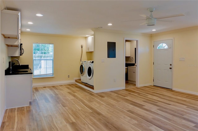 washroom with electric panel, light wood-style flooring, a sink, and washer and clothes dryer