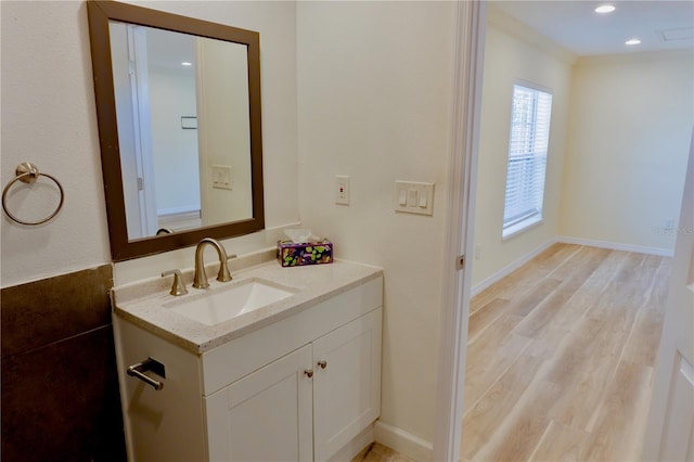 bathroom with recessed lighting, vanity, baseboards, and wood finished floors