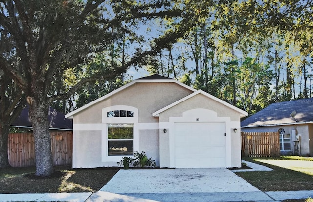 ranch-style house featuring a garage, driveway, fence, and stucco siding