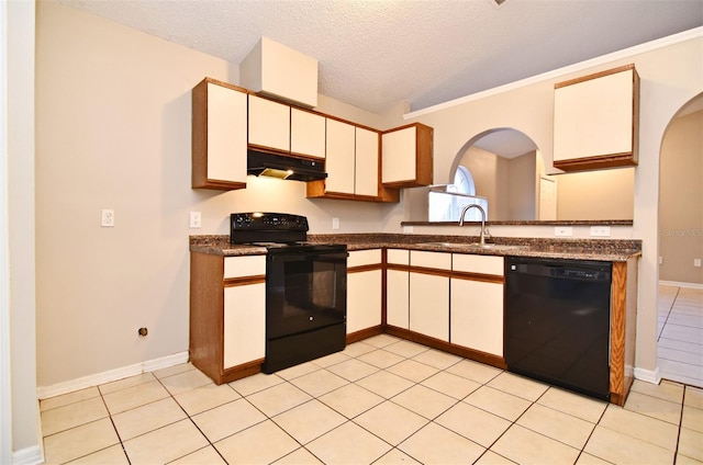 kitchen with arched walkways, dark countertops, a sink, under cabinet range hood, and black appliances