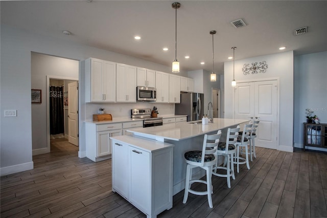 2720 Bancroft Blvd, Orlando, FL 32833 - kitchen with white cabinetry, appliances with stainless steel finishes, dark wood finished floors, a kitchen island with sink, and decorative backsplash