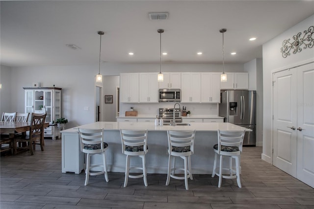 2720 Bancroft Blvd, Orlando, FL 32833 - kitchen with light countertops, wood finish floors, stainless steel appliances, a sink, and a kitchen island with sink