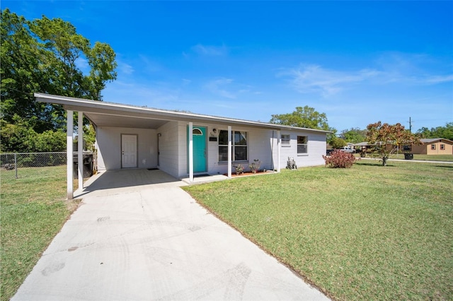 ranch-style house with an attached carport, a front lawn, fence, concrete driveway, and concrete block siding