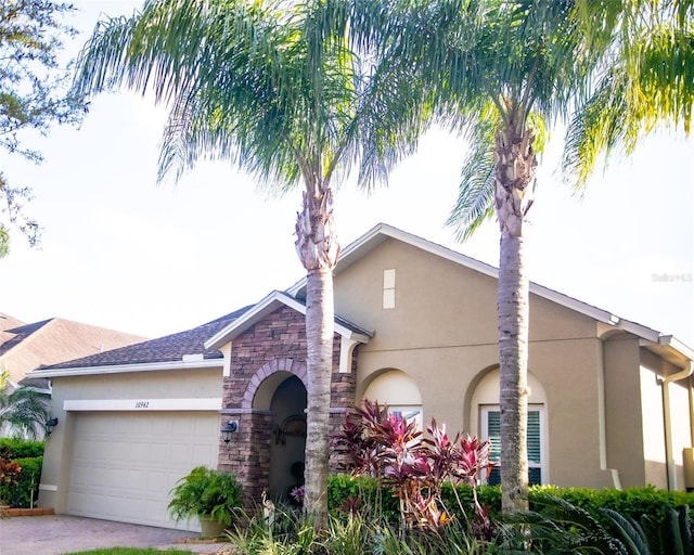 view of front of house featuring stone siding, stucco siding, driveway, and a garage