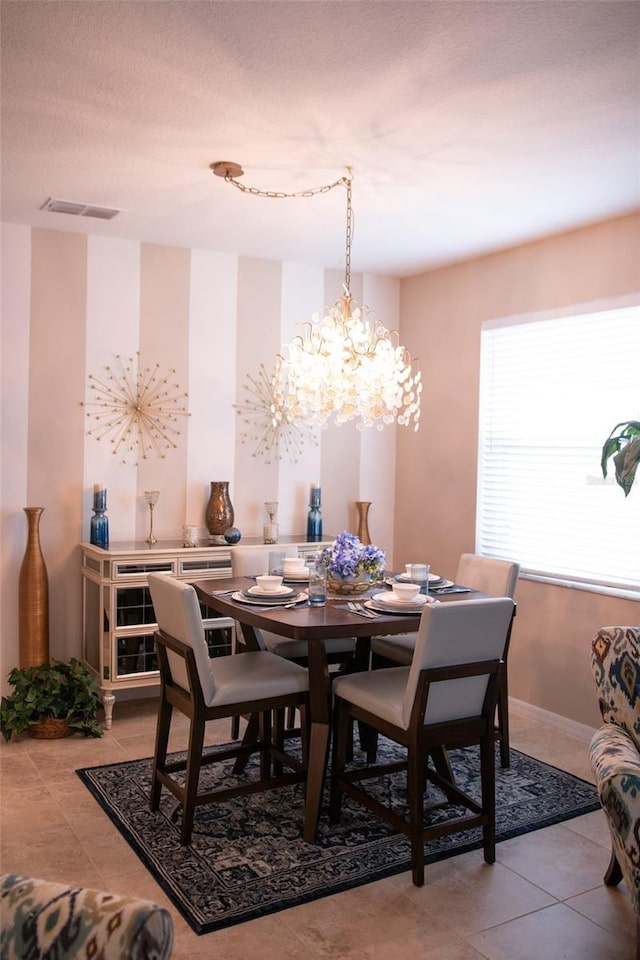 tiled dining area featuring visible vents, baseboards, and a textured ceiling