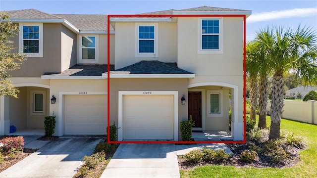 multi unit property featuring a garage, fence, concrete driveway, roof with shingles, and stucco siding