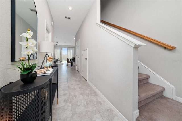 corridor with light tile patterned floors, visible vents, baseboards, and stairs