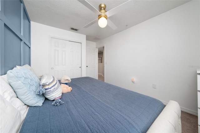 carpeted bedroom with a textured ceiling, ceiling fan, visible vents, baseboards, and a closet