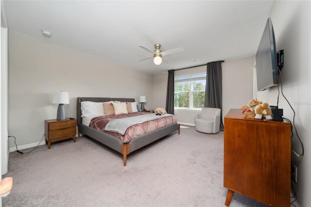 bedroom featuring light carpet, a textured ceiling, baseboards, and a ceiling fan