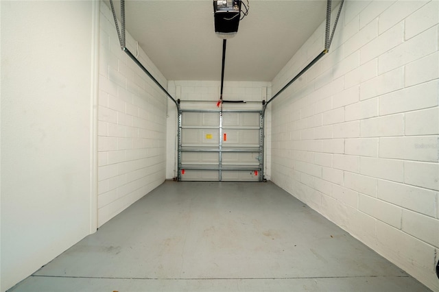 garage featuring concrete block wall and a garage door opener