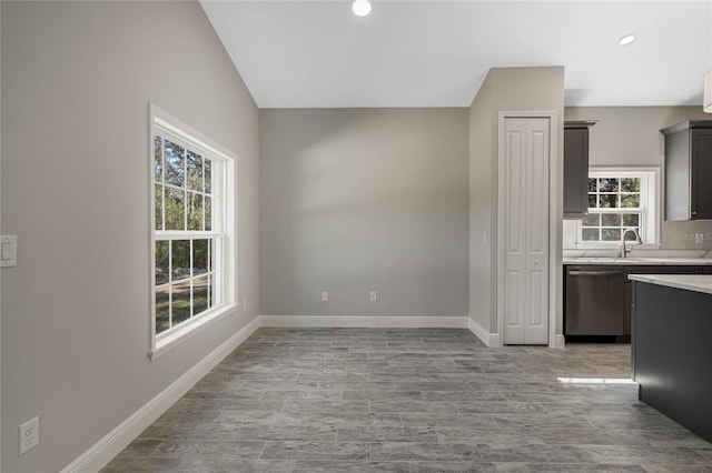 kitchen featuring light countertops, light wood-style flooring, a sink, dishwasher, and baseboards